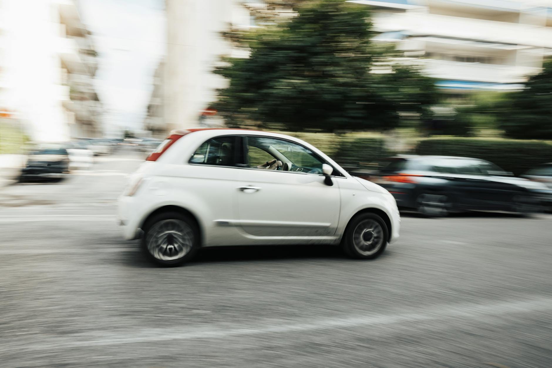 Białe Mitsubishi Colt pędzące po miejskiej ulicy z rozmytym tłem