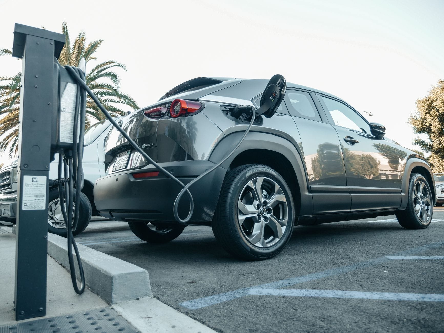 Elektryczny SUV ładuje się na zewnętrznej stacji w słoneczny dzień