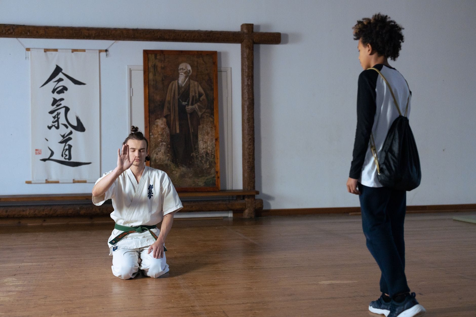 Instruktor aikido klęczy i uczy dorosłego ucznia w tradycyjnym dojo