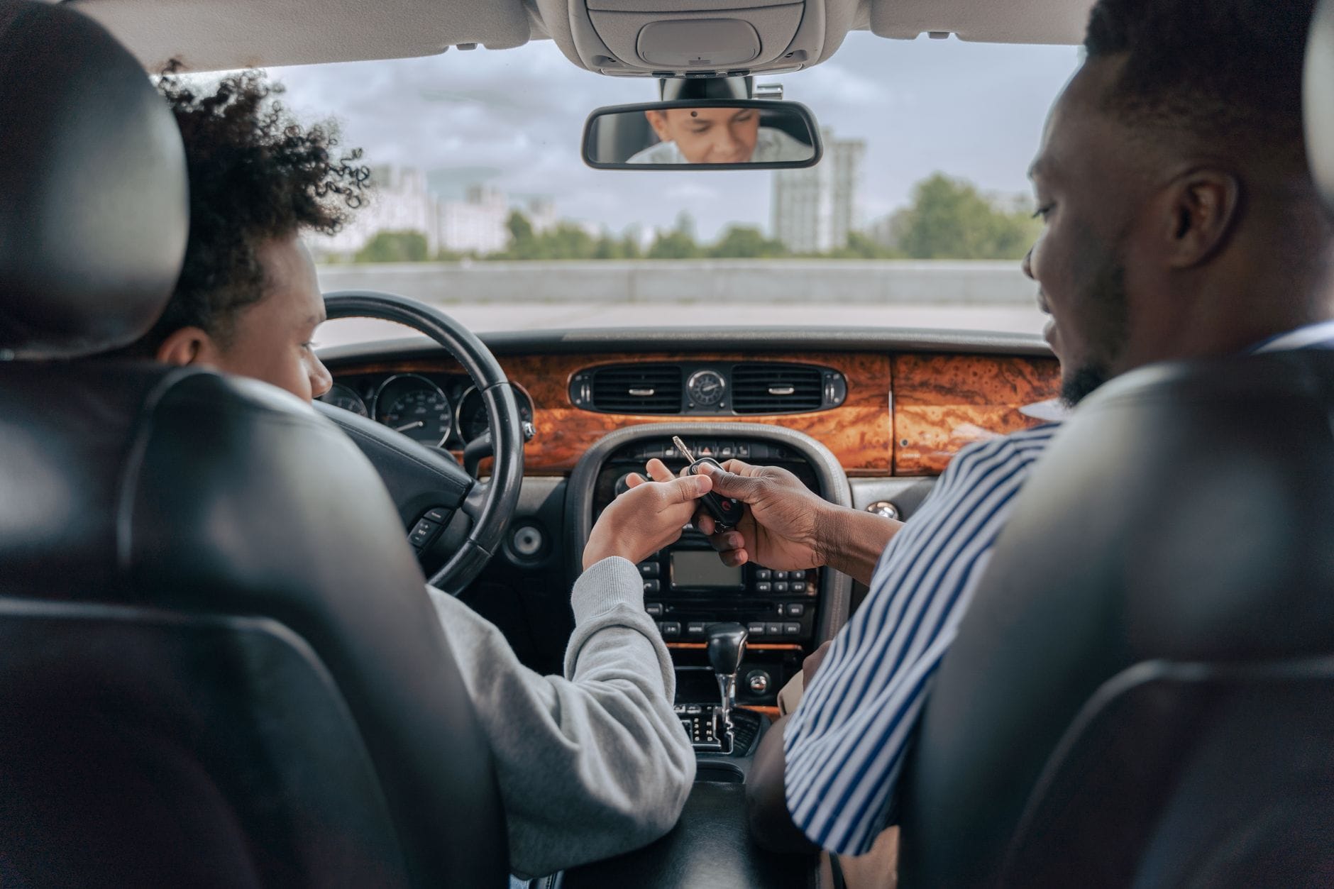 Ojciec uczy nastoletniego syna prowadzić auto, rozmawiają w środku auta