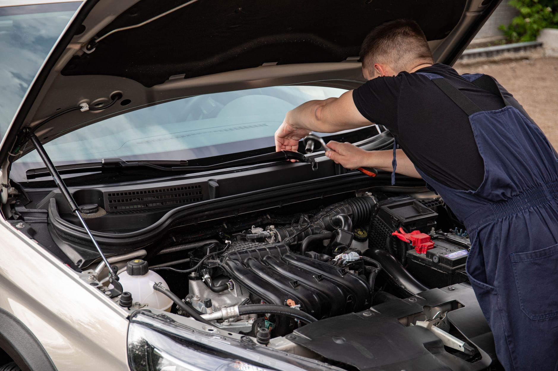 Mechanik naprawia silnik Subaru na zewnątrz w słoneczny dzień