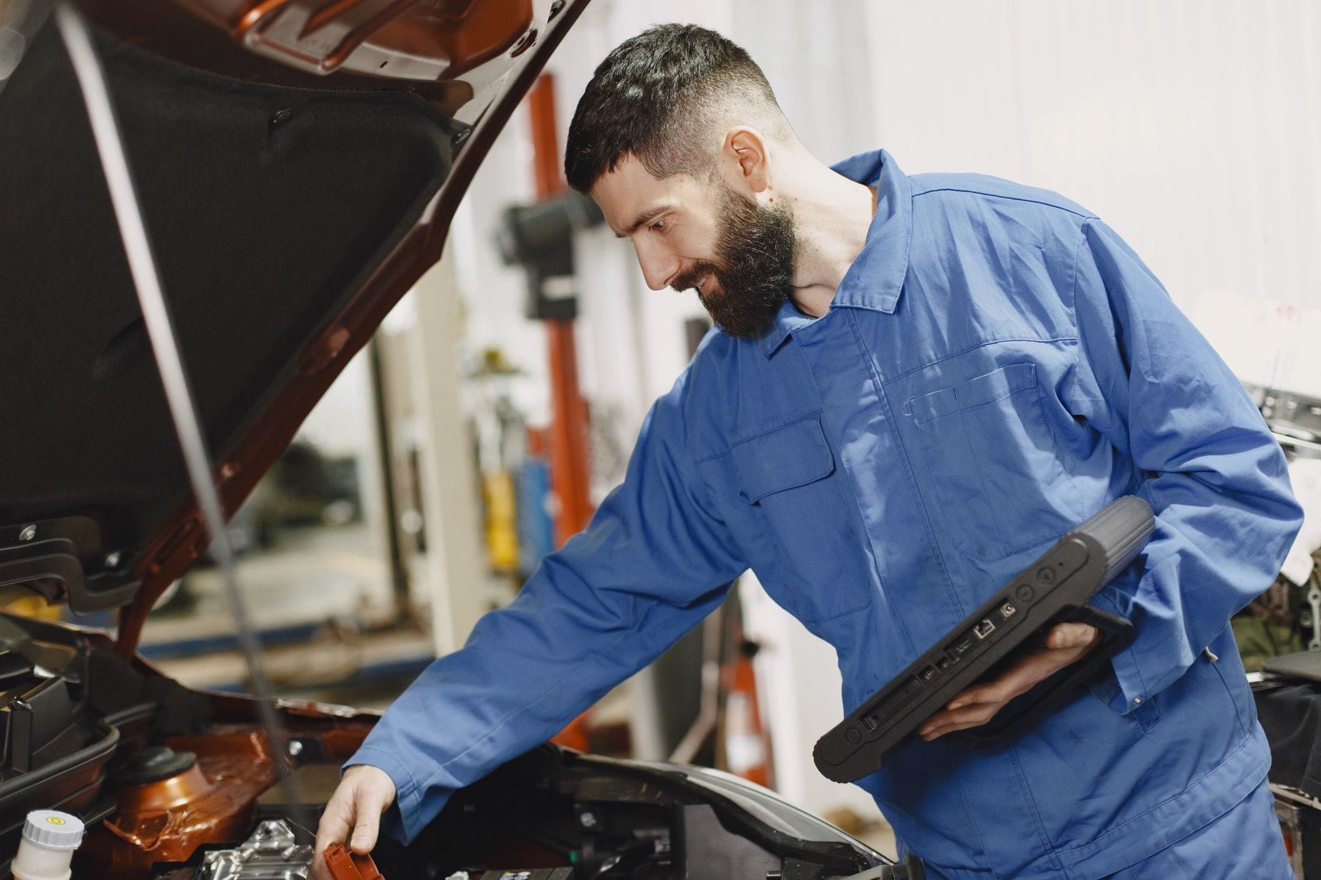 Mechanik w niebieskim kombinezonie sprawdza silnik Subaru w warsztacie