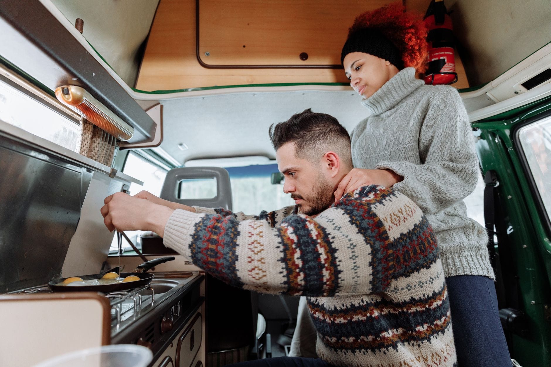 Para przygotowuje śniadanie we wnętrzu przytulnego kampera Ford Transit