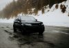 Czarny SUV na mokrej, ośnieżonej górskiej drodze wśród drzew
